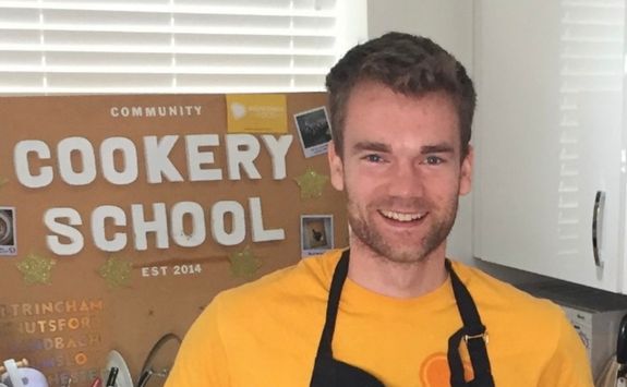Duncan standing in kitchen wearing his Bounceback uniform and apron.